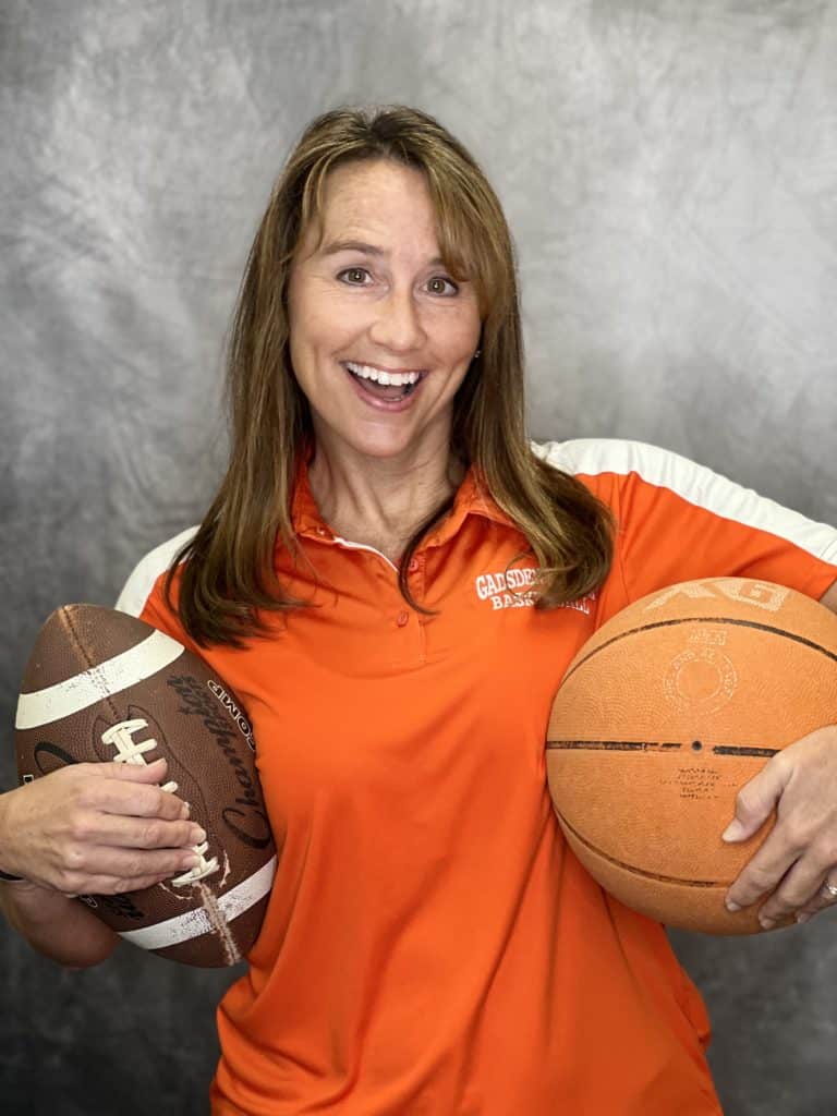 Mrs. Guthrie holding a football and basketball